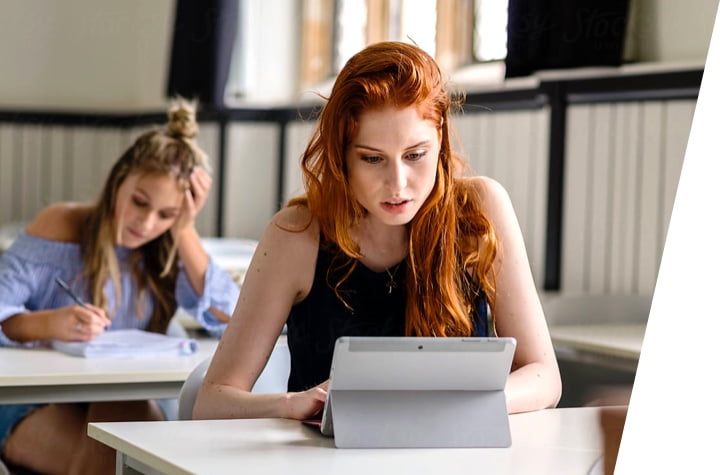一张红头发的女孩和一个金发的头发女孩在iPad上工作的照片